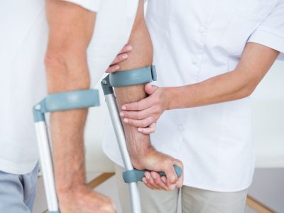 doctor-helping-her-patient-walking-with-crutch